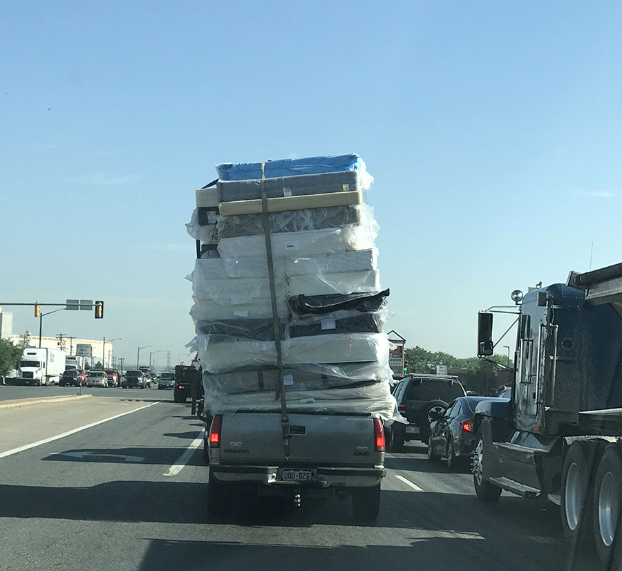 A photo of a pickup carrying about 25 mattresses in its bed.
